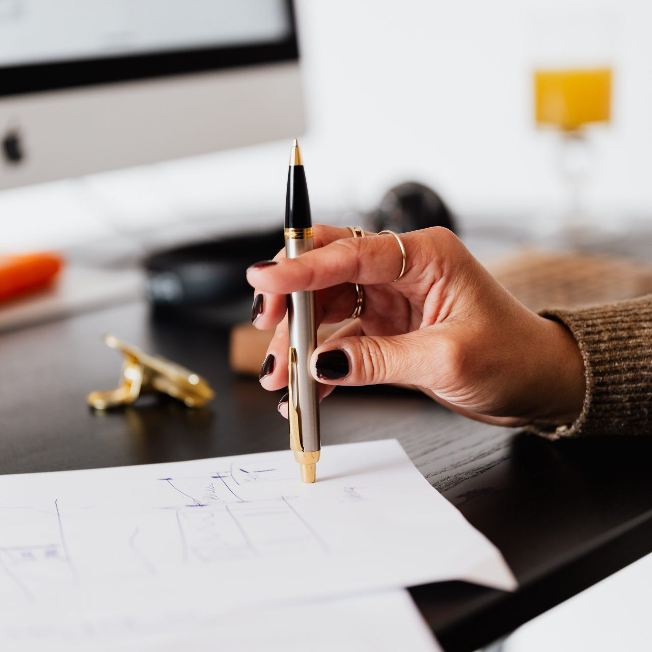 female hand with black nail polish holding a pen